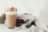 A glass of iced coffee with whipped cream and a drizzle of berry syrup, placed next to a crumpled linen cloth.